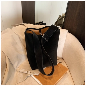 Detail der schwarzen Eimertasche aus Leder mit Silberschnalle auf beigem Sofa