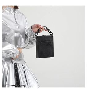 Detail of black faux snake skin bag featuring a chunky acrylic chain handle and zipper