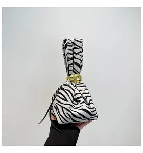 Detailed view of black and white zebra pattern fabric handbag with gold metal ring handle