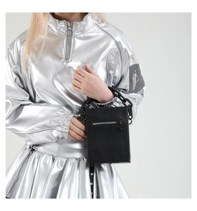 Detailed close-up of a black textured leather crossbody bag with chunky chain handle