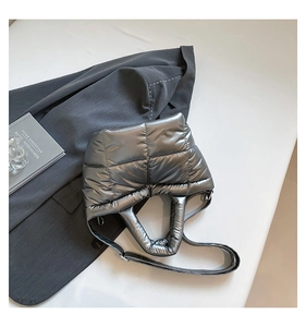Detail of the metallic silver quilted down fabric texture and padded handle of the tote bag