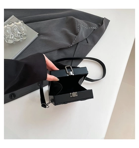 Detailed view of the black box-shaped bag showing the metal clasp and accordion interior