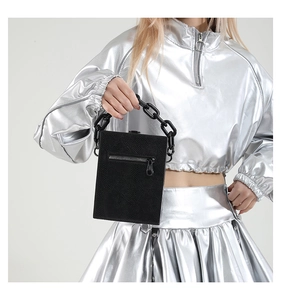 Detail of black textured leather crossbody bag with chunky chain handle and silver zipper