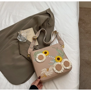 Detailed close-up of sunflower embroidery and jacquard strap on a chic crossbody bag