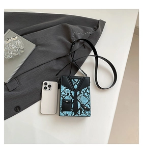 Detail of blue python-pattern crossbody bag with creative suit and tie design elements