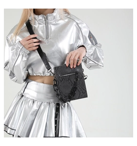 Detail of black snake pattern crossbody bag featuring chunky chain and metal zipper
