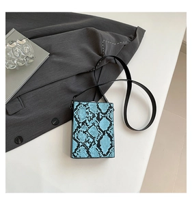 Detailed top view of light blue snakeskin box bag with sleek black strap and modern design