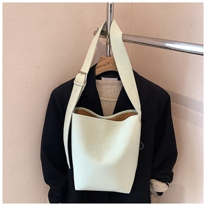 Detailansicht der cremefarbenen Beuteltasche mit breitem Gurt und Metallschnalle am Blazer