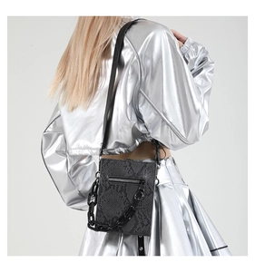 Detail of black snake pattern crossbody bag with resin chain on metallic outfit
