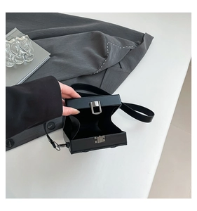 Detail view of the spacious inner compartment of the black hard shell box crossbody bag