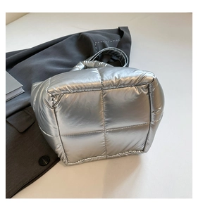 Detail of silver quilted puffer tote bag with metallic texture and padded handle