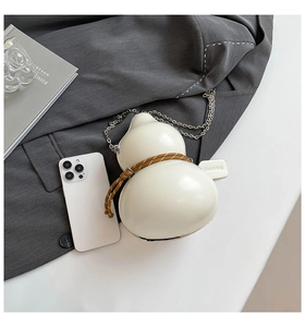 Detail view of cream gourd bag with brown rope accent and silver chain strap