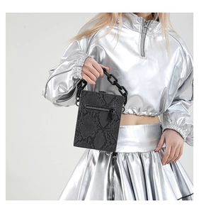 Detail of black snake pattern texture and chunky chain handle on small crossbody bag