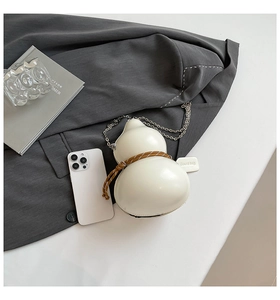Macro detail of creamy white gourd-shaped crossbody bag with woven cord and metal chain