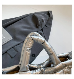 Detailed macro view of silver quilted down tote bag with metallic glossy fabric finish