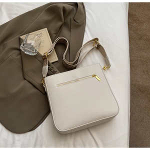 Detail of cream crossbody bag with bohemian patterned strap and gold zipper pocket