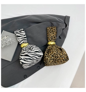 Close-up of animal print canvas mini handbags with elegant golden metal ring buckles