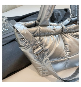 Detailed side view of silver quilted puffer bag with metal buckle and adjustable strap