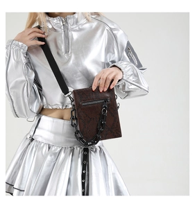 Detailed macro view of brown snakeskin texture and thick black acrylic chain on a small bag