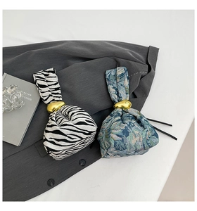 Detail of zebra pattern and floral knot handbags with gold rings on a blazer
