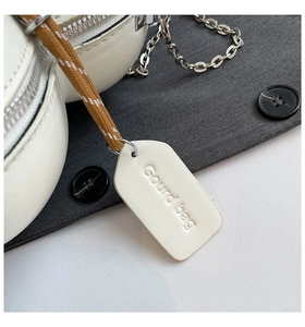 Detailed macro view of white leather gourd-shaped bag with woven strap and silver zipper