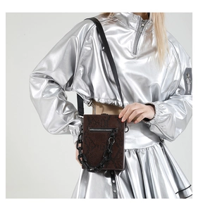 Detail of dark brown snakeskin crossbody bag featuring chunky black chain and zipper