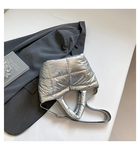 Detail of silver quilted puffer tote bag featuring metallic finish and padded handles