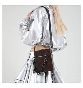 Detail view of dark brown snakeskin embossed crossbody bag with black resin chain and strap