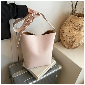 Detail der hellrosa Handtasche mit Kieseltextur, breitem Gurt und goldenen Beschlägen