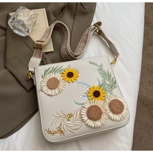 Close-up of sunflower and daisy floral embroidery on white PU leather crossbody bag