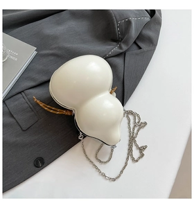 Detailed view of cream-white gourd-shaped crossbody bag with metal chain on grey blazer
