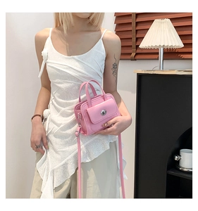 Detail of pink leather handbag featuring a silver twist lock and adjustable shoulder strap