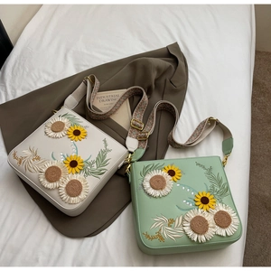 Detail of floral sunflower embroidery on leather crossbody bags with jacquard strap