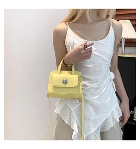 Model wearing vibrant yellow mini leather handbag with silver twist lock and lace dress