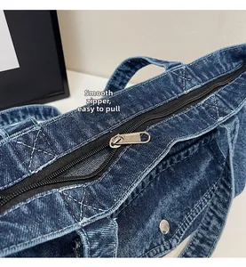 Close-up of smooth metal zipper and white stitching detail on blue denim tote bag