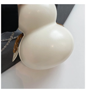 Detail showing the cream faux leather texture and braided rope of the gourd-shaped bag