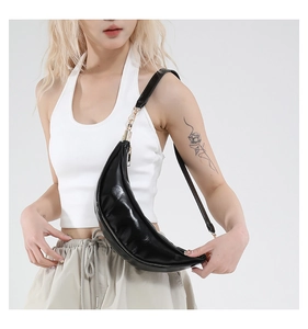 Detail of glossy black crescent chest bag showing premium PU leather texture and gold metal hooks