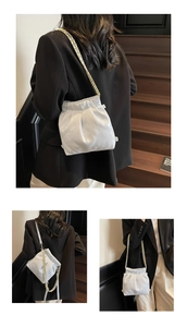 Detail of white quilted bucket bag with gold chain strap shown on a wooden staircase