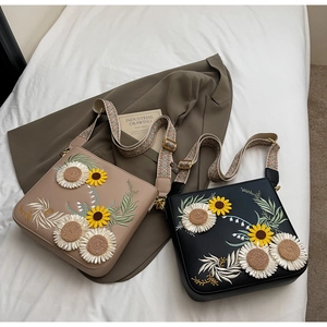 Close-up of sunflower embroidery and wide woven strap on American pastoral style crossbody bag