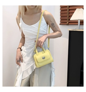 Detail of yellow leather crossbody bag with silver buckle worn on a white dress