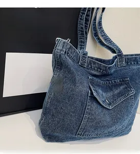 Detail of vintage blue denim tote bag showing reinforced stitching and front flap pocket