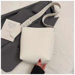 Detailansicht der beigen Eimer-Tasche aus Leder mit breitem, verstellbarem Schultergurt