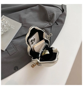 Interior capacity detail of cat-ear crossbody bag showing phone, lipstick, and notepad