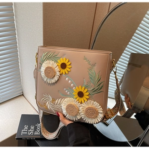 Close-up of beige crossbody bag with floral sunflower embroidery and woven strap