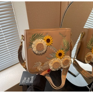 Detail of floral embroidery on beige crossbody bag with patterned shoulder strap