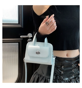 Close-up of light blue mini satchel with silver twist-lock and slim crossbody strap