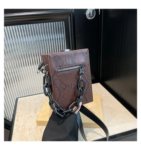 Detail view of brown snakeskin pattern bag with chunky black chain and side zipper