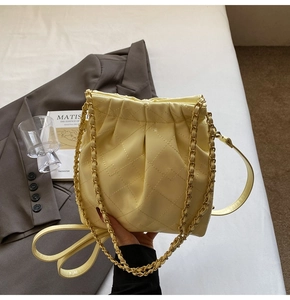 Close-up of cream quilted bucket bag with chain strap and soft leather diamond pattern