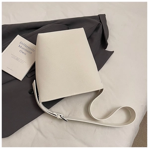 Detail der minimalistischen cremefarbenen Beuteltasche auf grauem Blazer mit Lederstruktur