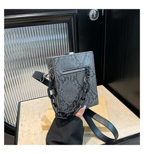 Detail of snake skin texture small square bag with chunky black chain and metal zipper